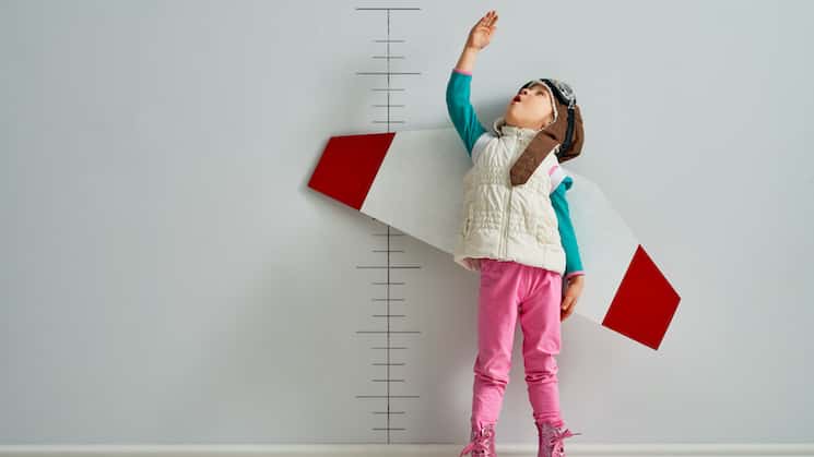 Child with wings measuring their height on wall.
